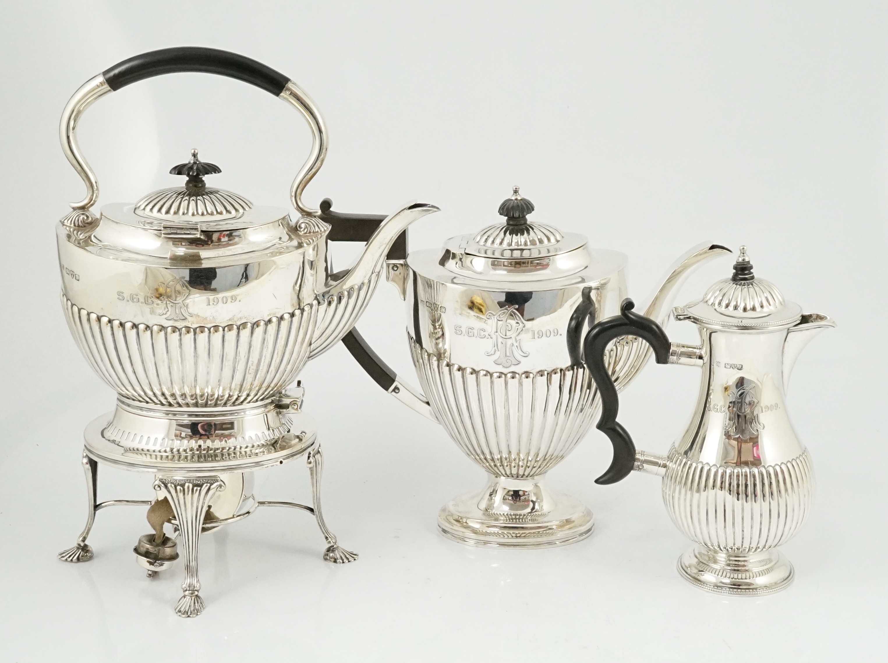 An Edwardian demi-fluted silver tea kettle on stand with burner, with matching pedestal coffee pot and hot water pot, by Barker Brothers